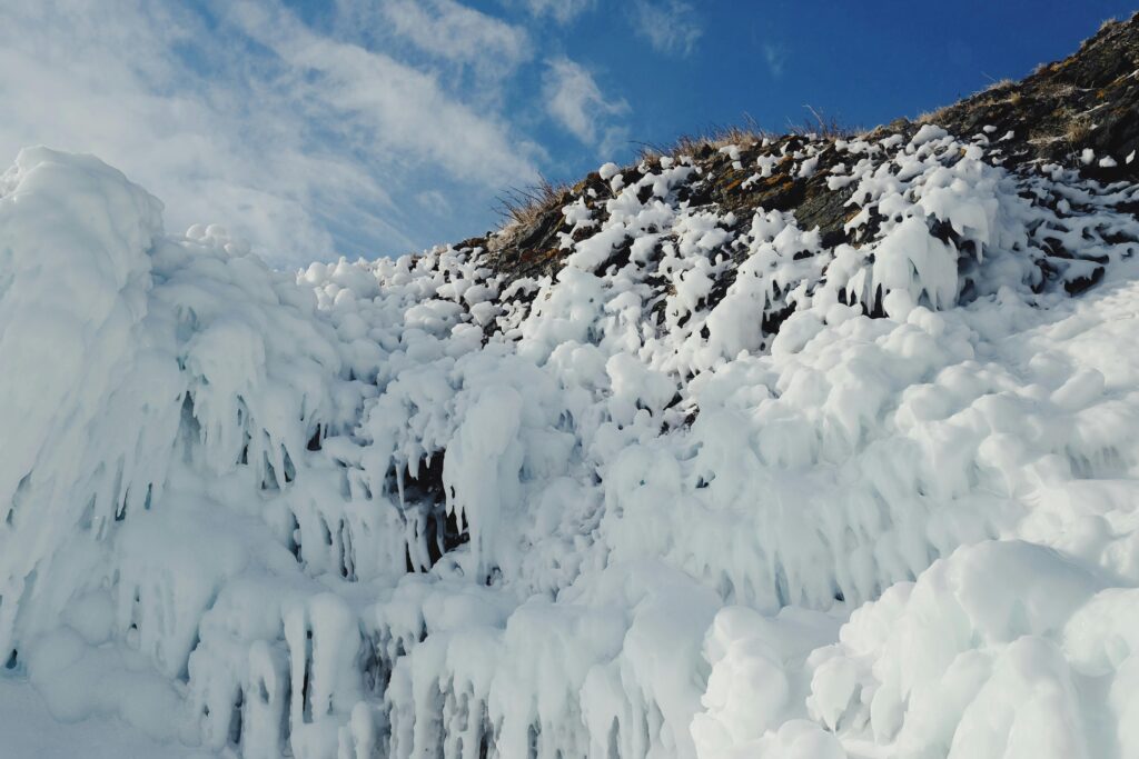 Stunning winter landscape of ice-covered rocky slope under clear sky, showcasing nature's beauty.